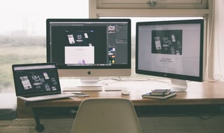 Laptop on a desk with two monitors