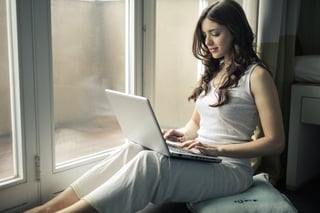 Business owner using their laptop on a window ledge