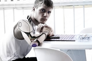 Individual sitting at a desk with robotic arms