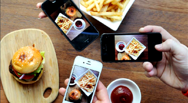Individual taking photos of their food on a table